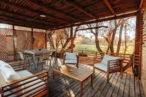 um deque com cadeiras, mesas e uma mesa em Peumayen Atacama cabaña&Hostal em San Pedro de Atacama