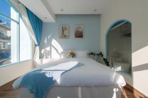 1 dormitorio con cama blanca y ventana en Moc Thach Blue House DaLat, en Da Lat