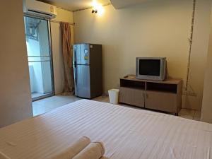 OYO 75417 Grandview Condominia في بانكوك: غرفة بسرير وتلفزيون وثلاجة
