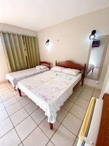 a bedroom with two beds and a mirror at Pousada Do Vozinho in Touros