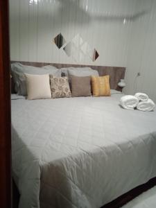 Elle comprend un grand lit blanc avec des oreillers. dans l'établissement Hospedagem Don Panizzi, à Bento Gonçalves