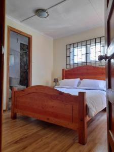 - une chambre avec un grand lit en bois et une fenêtre dans l'établissement Casa Avenida Alemania, à Valparaíso