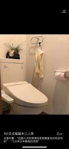 東洋の家-畳み部屋小庭園 في طوكيو: حمام مع مرحاض أبيض ومنشفة