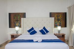 a bedroom with a large white bed with blue pillows at Matahari Inn Kuta Lombok in Kuta Lombok