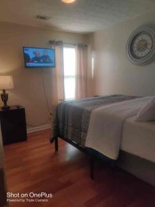 een slaapkamer met een bed en een tv aan de muur bij Cozy private rooms in Jonesboro