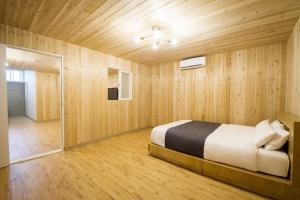 een slaapkamer met een bed en een houten muur bij Haedenville Pension in Seogwipo