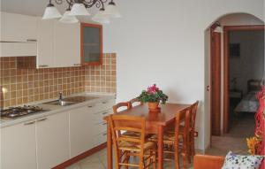 een keuken met een houten tafel met stoelen en een wastafel bij Nice Apartment In Valledoria With Outdoor Swimming Pool And 1 Bedrooms in Valledoria