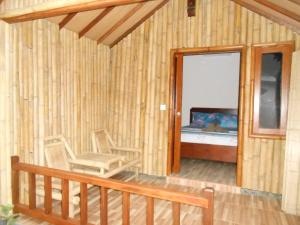 Habitación de madera con 2 sillas y 1 cama en Sari Laut, en Gili Meno