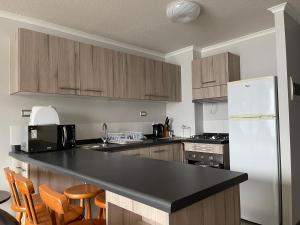 a kitchen with a white refrigerator and wooden cabinets at Apartamento junto a la playa en Bahía Horizonte in Coquimbo