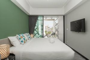 a bedroom with a large white bed and a window at Yanud Residence in Phuket Town
