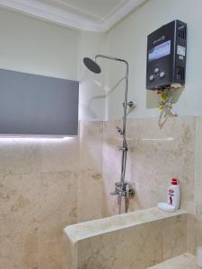 a shower in a bathroom with a sink and a tv at Medewi Manor in Airsatang