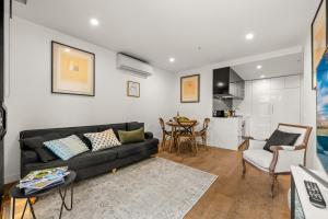 sala de estar con sofá negro y mesa en StayCentral - Hawthorn East - Study, 2 Car spaces en Melbourne