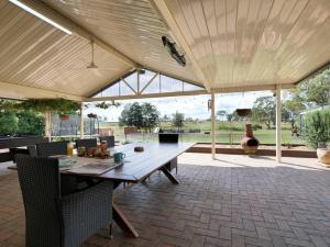 um pavilhão com uma grande mesa de madeira e cadeiras em Lilly Pilly Lodge em Wallalong