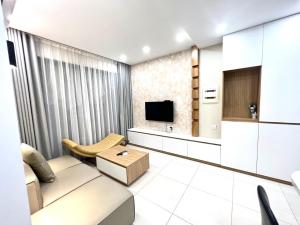 uma sala de estar com um sofá e uma televisão em vinhomes dcapitale 1 phòng ngủ em Hanói