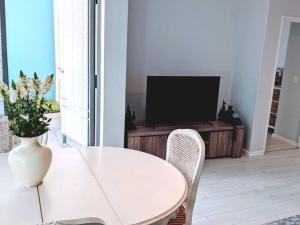 a white table and chairs in a living room with a television at On The Beach at Surfers Corner in Cape Town