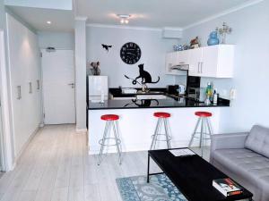 a kitchen and a living room with a couch and a table at On The Beach at Surfers Corner in Cape Town