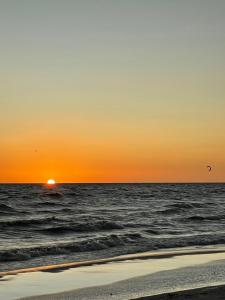 una puesta de sol sobre el océano con aves volando en el cielo en Altos de Kiyu, en José Ignacio