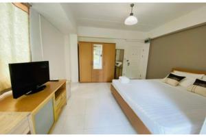 OYO 75418 Grandview Place في بانكوك: غرفة نوم بسرير كبير وتلفزيون بشاشة مسطحة