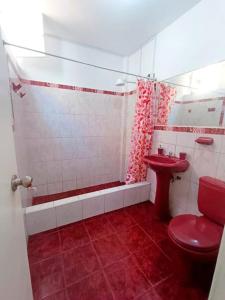 Baño rojo con aseo rojo y lavamanos en Casa de Playa Barranca, en Barranca