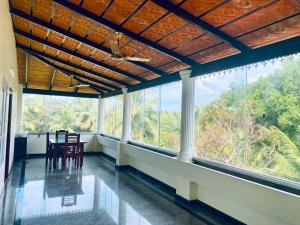 a room with chairs and large windows with trees at Gloria Homes in Nāgercoil