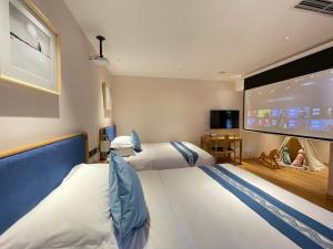 ein Hotelzimmer mit 2 Betten und einem großen Bildschirm in der Unterkunft Beijing Heyuan Courtyard Hotel (Forbidden City) in Peking