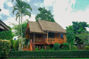 a wooden house with a deck and a palm tree at Pai Homey in Pai