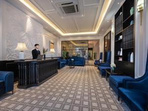 a man standing at a reception desk in a hotel lobby at The Flower Boutique Hotel & Travel in Hanoi