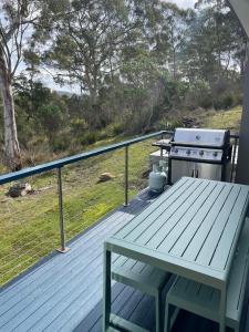 a wooden deck with a picnic table and a stove at Hill Top Retreat in Nubeena