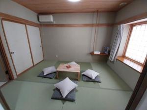een lege kamer met een tafel en kussens op de vloer bij Miyuki Townhouse in Furano