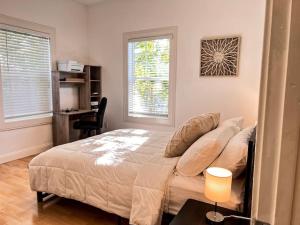 a bedroom with a bed and a desk and two windows at Comfortable 2BR Spacious Deck! 7 mins to Sacramento Downtown and Midtown in Sacramento