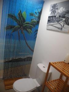 La salle de bains est pourvue de toilettes et d'une fresque murale de palmiers. dans l'établissement Les jardins d'Émilie, à Le Moule
