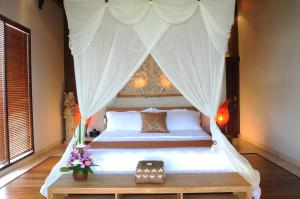 a bedroom with a bed with a canopy at Villa DiKebun in Uluwatu +26 photos