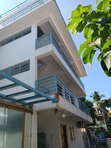 a white house with blue balconies on it at Sai Leela Guest House in Dabolim