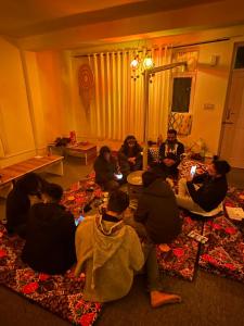 a group of people sitting on the floor in a living room at La Heim Hostels in Manāli