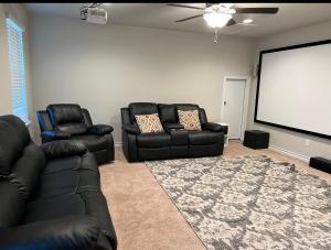 a living room with two black leather chairs and a screen at Beautiful Home with Modern Rooms in Round Rock