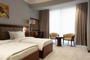 a hotel room with two beds and a table and chairs at Mir Luxe Plaza in Tashkent