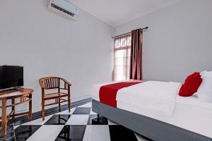 Schlafzimmer mit einem Bett, einem Schreibtisch und einem TV in der Unterkunft OYO 92067 Sekar Gadung Homestay Syariah in Yogyakarta