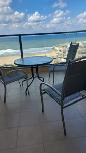 stół i krzesła na balkonie z plażą w obiekcie Blue Sea Suite w mieście Aszkelon