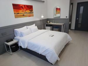 a bedroom with a large white bed and a table at Hi& Hotel in Pyeongtaek