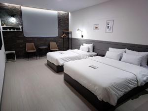 a hotel room with two beds and a projection screen at Hi& Hotel in Pyeongtaek
