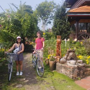 芹苴的住宿－Brown House Resort，两名妇女站在花园里,骑着自行车