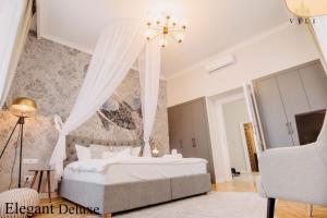 - une chambre avec un lit blanc et un lustre dans l'établissement Vili Apartments, à Oradea