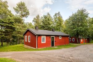 uma cabana vermelha com um telhado preto numa estrada de terra batida em First Camp Hökensås-Tidaholm em Tidaholm