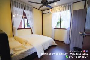 1 Schlafzimmer mit 2 Betten und 2 Fenstern in der Unterkunft Homestay Segamat - Villa Seri Intan in Segamat