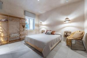 a white bedroom with a bed and a chair at Sofisticado apartamento en frente a la playa in Málaga