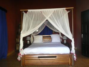 una camera con letto a baldacchino con lenzuola e cuscini bianchi di Bohobé Naboty a Toliara