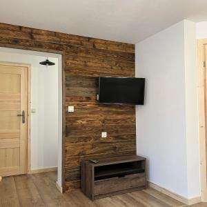 sala de estar con pared de madera y TV de pantalla plana en Pokoje u Danusi, en Czarna Góra