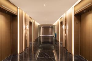 un pasillo de un hotel con paredes de madera y un largo pasillo de una habitación de hotel en HUALUXE Shanghai Changfeng Park, an IHG Hotel en Shanghái