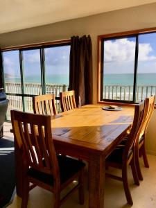 a wooden table and chairs with a view of the ocean at Panoramic Views - House in Ahipara