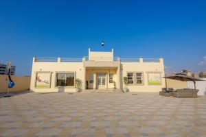 a large white building with an umbrella in front of it at Al Wadi House , بيت الوادي in Ras al Khaimah